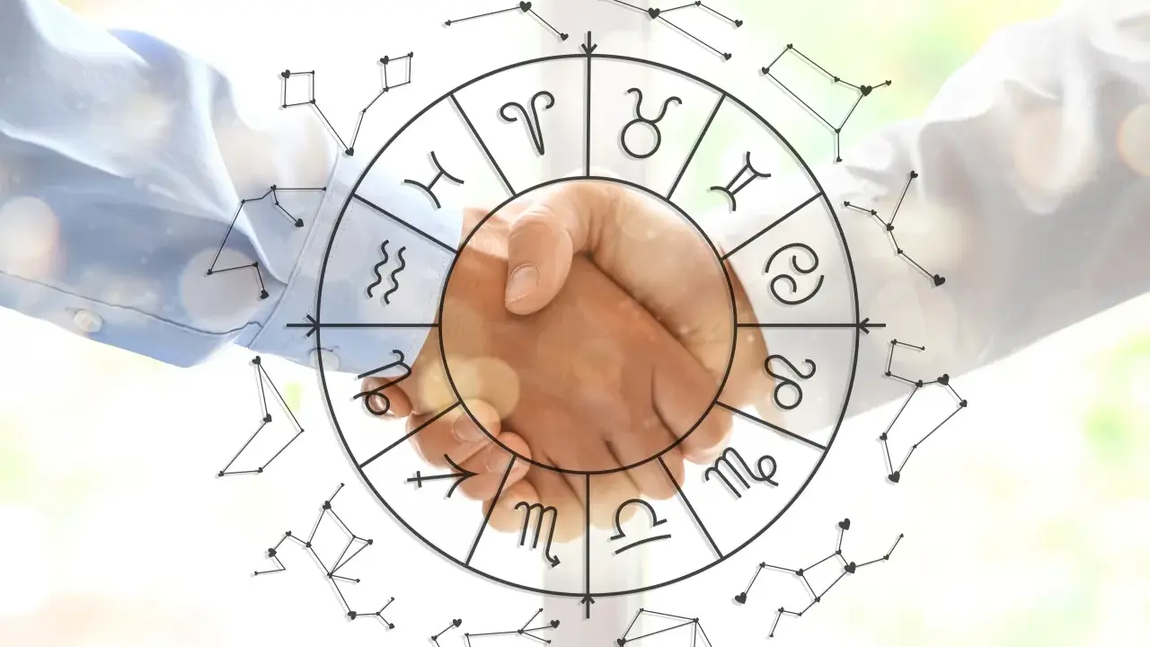 Dwie dłonie ściskają się na tle koła zodiaku i konstelacji. Astrologia i data urodzenia łączą ludzi.
