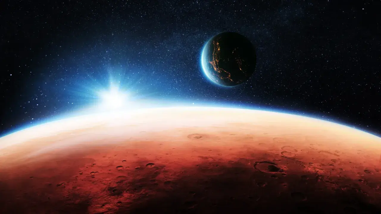 Czerwona planeta Mars wschodzi na tle gwieździstego nieba. W oddali widać Ziemię, rozświetloną światłami miast.