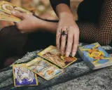 Ręka z pierścieniem w kształcie pająka rozkłada karty tarota. Czy to horoskop miesięczny lew tarot?