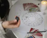 Astrologiczna mapa nieba z symbolami zodiaku, talie kart i świece. Wenus w Strzelcu zapowiada podróże i nowe znajomości.