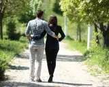 Para spaceruje alejką w parku, mężczyzna obejmuje kobietę. Ich związek jest jak pluton w wadze – harmonijny i pełen równowagi.